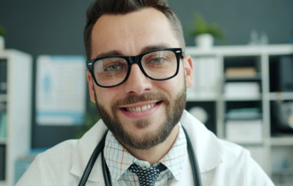 Smiling doctor wearing glasses and stethoscope in office